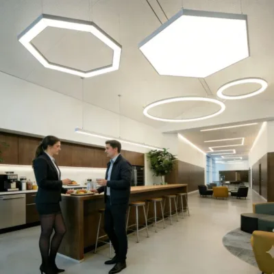 Een strakke, minimalistische kantoorkeuken met een vertakkend lineair lichtsystem dat zich uitstrekt over het plafond. De strakke architectonische lijnen zorgen voor schaduwvrije verlichting en benadrukken de hoogwaardige afwerking van een moderne Noord-Amerikaanse Klasse A-werkplek.