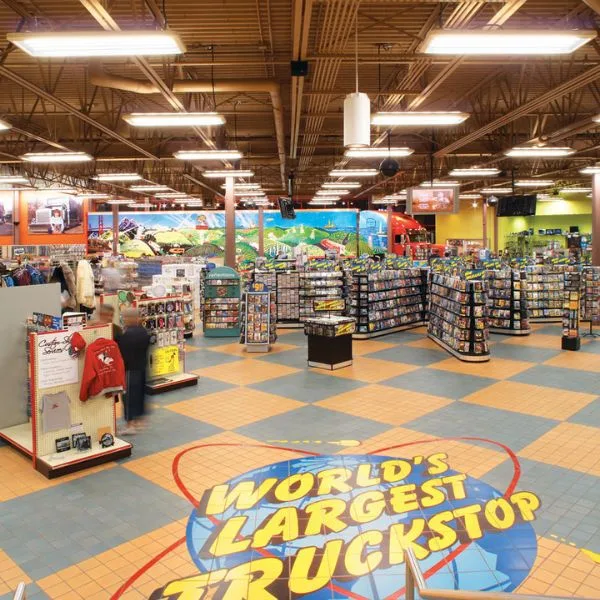 Luminária linear robusta de alta bay instalada com segurança em um ambiente industrial de grande varejo com teto alto.